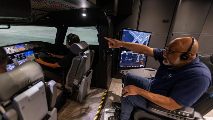 image shows simulator cockpit with evaluator behind two pilots