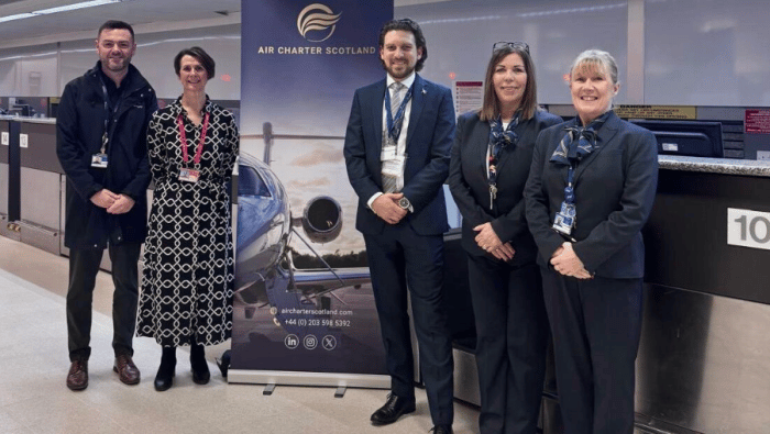 Crew at airport next to sign 