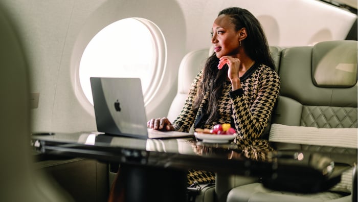 A woman sits in an aircraft cabin with her laptop