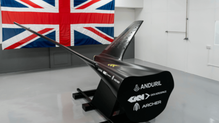 Mockup of tail and fuselage in front of Union Jack flag on wall 