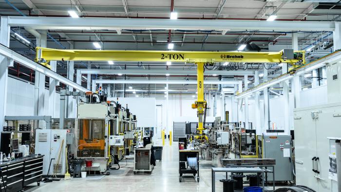 An interior shot of a brightly-lit advanced composite manufacturing production facility with clean concrete floors, moveable fixtures, overhead lift, and advanced tooling.