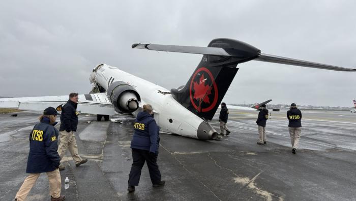 NTSB investigators walk the scene of the Mar. 22 collision between an Air Canada Express plane and a firefighting vehicle on Runway 4 at LaGuardia Airport.