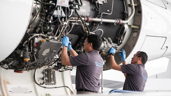 Two technicians inspecting open aircraft panel 