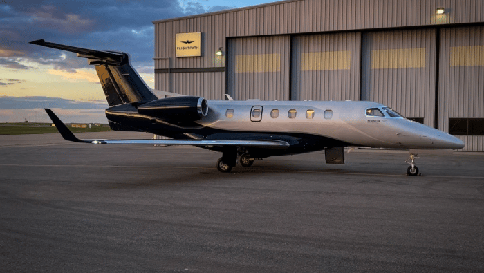 A Phenom 300E parked in front of the Flightpath hangar in Calgary at dusk