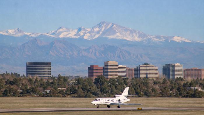 A jet taxiing at Englewood Aiport with buildings and the mountains in the background