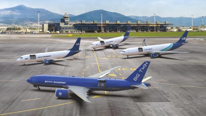 Four blue-and-white IAI converted freighters parked on an airport ramp, with a Boeing 777-300ERSF in the foreground