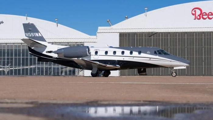 a business jet in front of a hangar