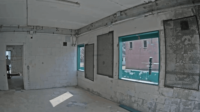 Small drone hovering in window of breeze-block room 