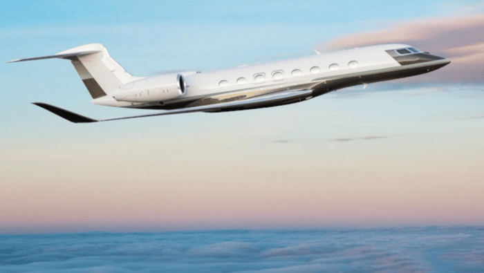 A Gulfstream G800 in flight above clouds at dusk