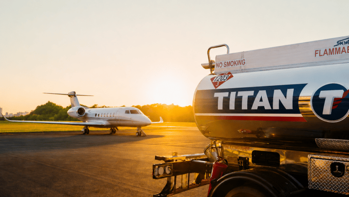 A Titan branded fuel truck in the foreground with a business jet on the ramp in the background