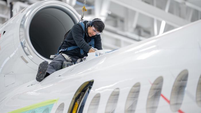 a mechanic works on inspecting a business jet in a maintenance hangar