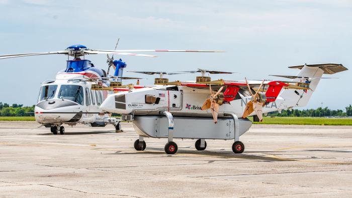 Elroy Air’s hybrid-electric Chaparral cargo drone is parked beside a helicopter from Bristow