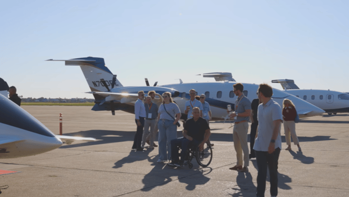 Group of people on ramp, three aircraft behind 