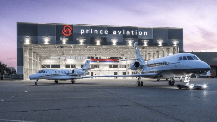 Two jets on ramp outside maintenance hangar at night time 
