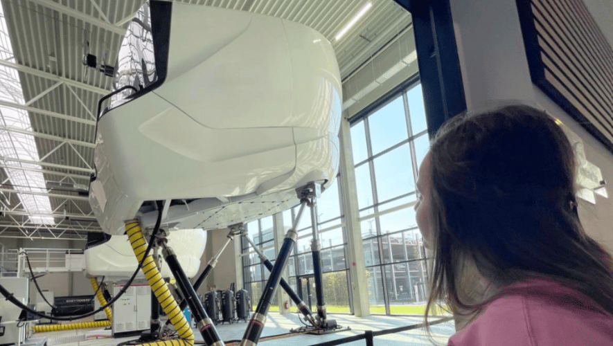 Girl looking at full-motion flight simulator 