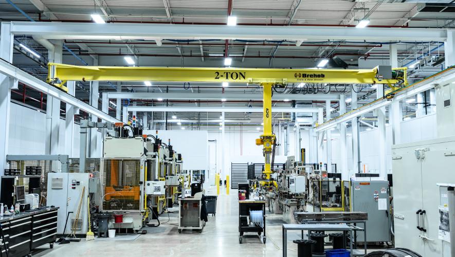 An interior shot of a brightly-lit advanced composite manufacturing production facility with clean concrete floors, moveable fixtures, overhead lift, and advanced tooling.