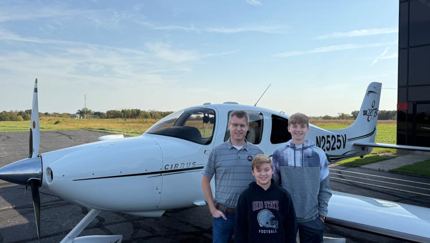 a pilot and two kids pose in front of a small GA aircraft