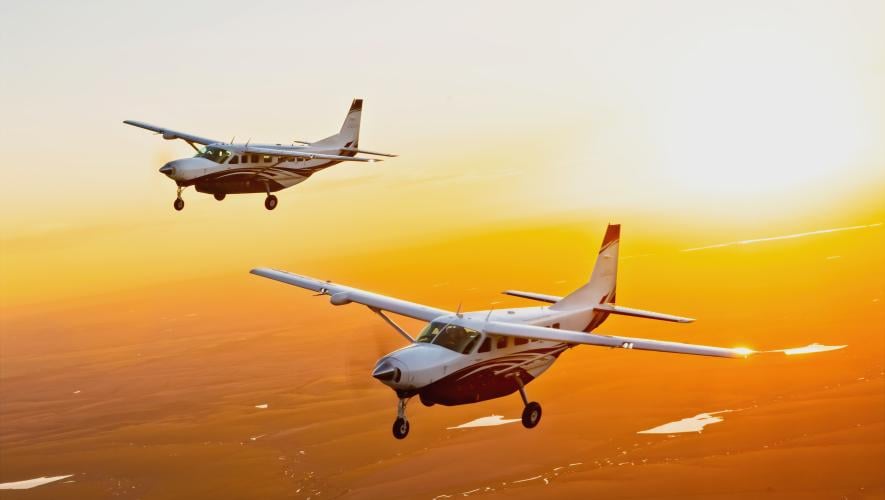 Two Cessna Caravans in flight against sunset 