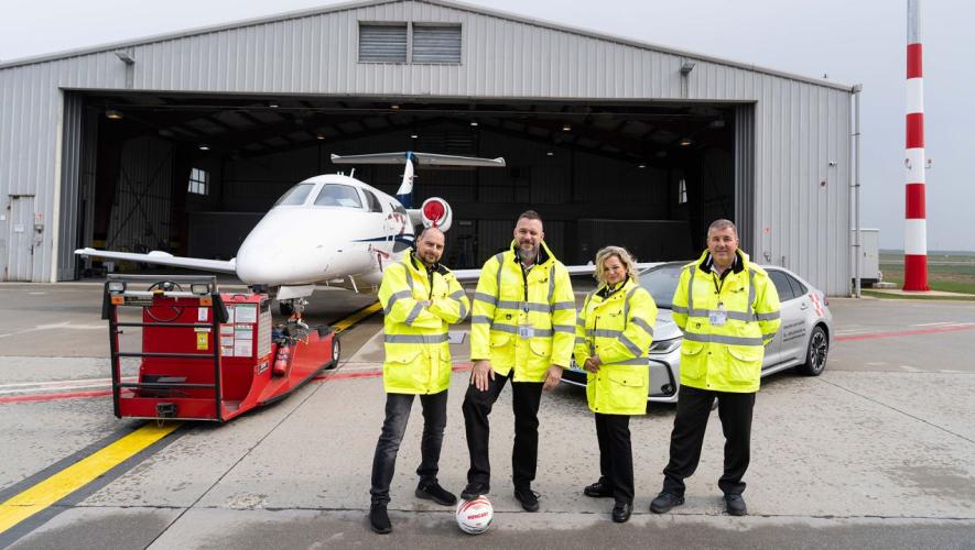 four people standing outside hangar 