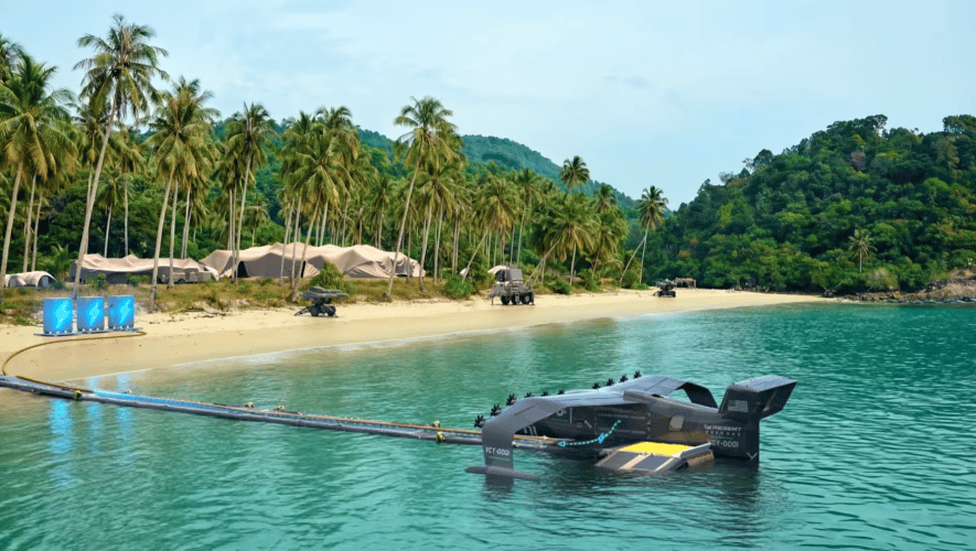 A rendering shows a Seaglider tethered to modular battery storage units on a remote beach, illustrating the off-grid charging concept.