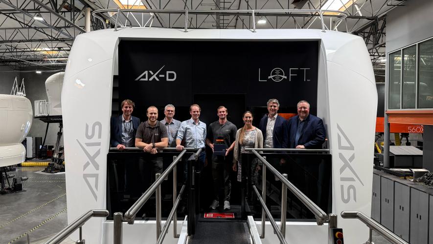 People standing in front of flight simulator in hangar 