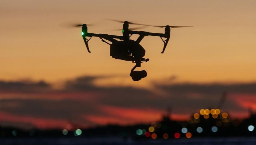 Drone flying over water at sunset 