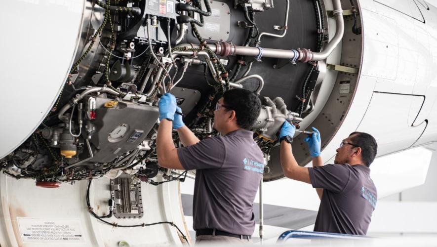 Two technicians inspecting open aircraft panel 