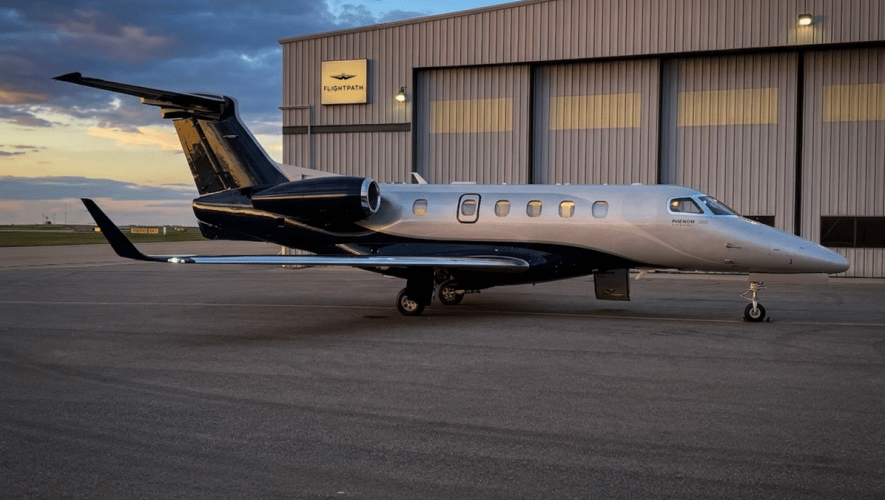 A Phenom 300E parked in front of the Flightpath hangar in Calgary at dusk
