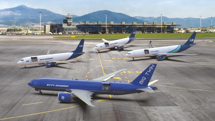 Four blue-and-white IAI converted freighters parked on an airport ramp, with a Boeing 777-300ERSF in the foreground