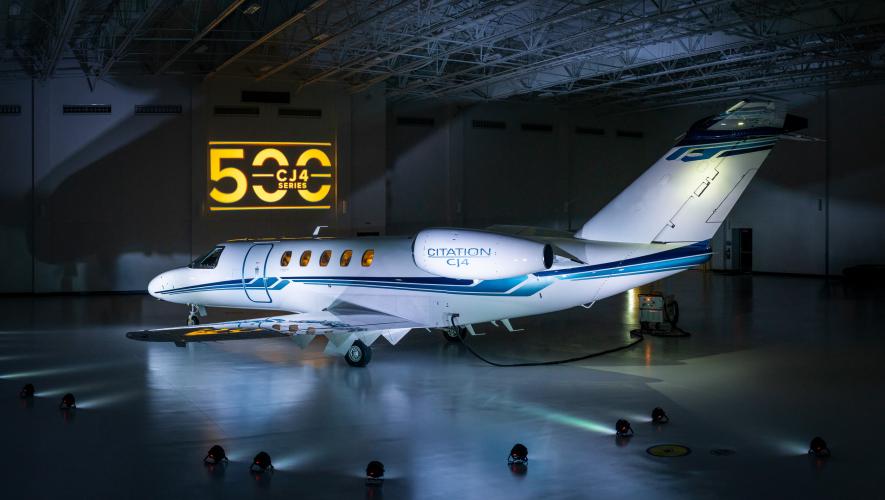 A Citation CJ4 lit dramatically in a hangar with the number 500 projected on the wall behind it