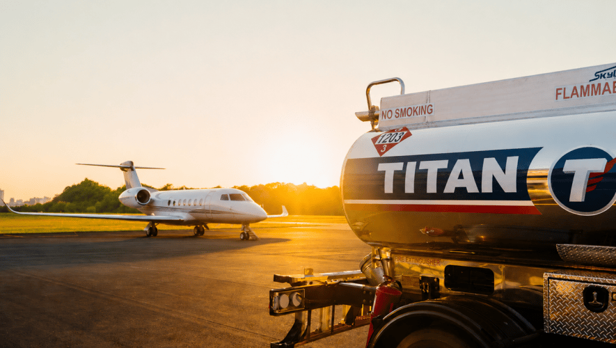 A Titan branded fuel truck in the foreground with a business jet on the ramp in the background