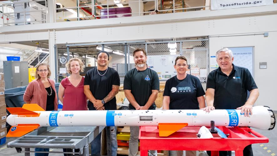 Starfighters Space CEO Tim Franta (right) stands with an inert Wind Tunnel in the Sky carrier on October 16 in a receiving area next to Bionetics’ payload processing lab in Florida.