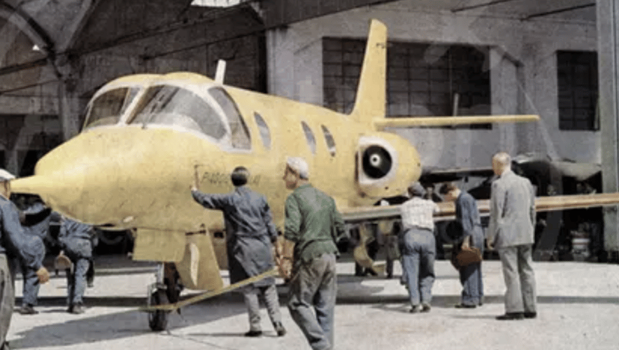 Unpainted Vespa Jet with workers in hangar 