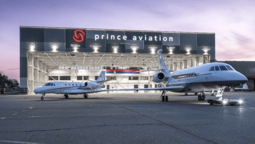 Two jets on ramp outside maintenance hangar at night time 