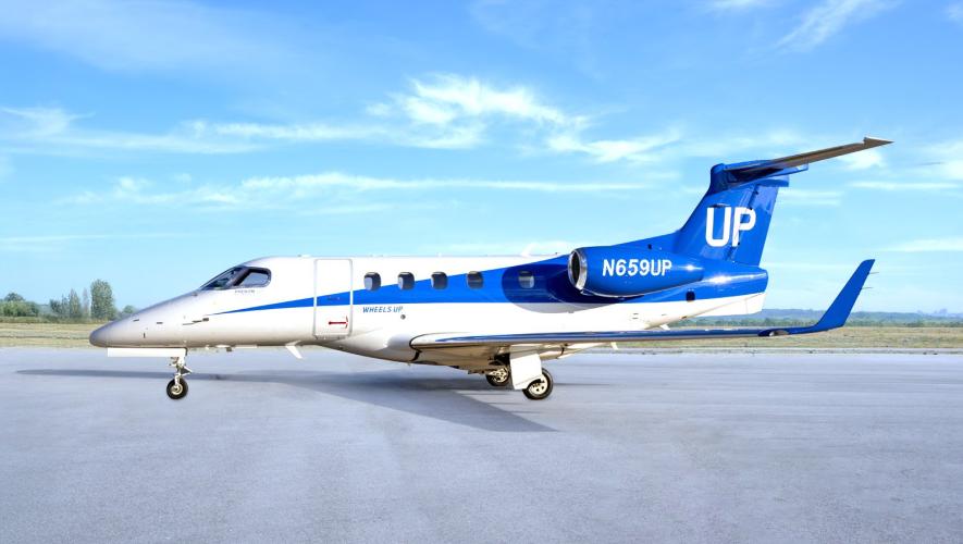 Blue and white Wheels Up liveried Phenom 300 on tarmac 