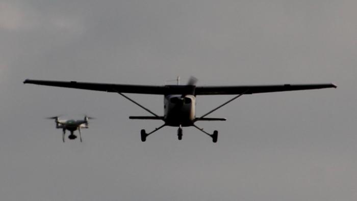 A light aircraft in flight near a drone.