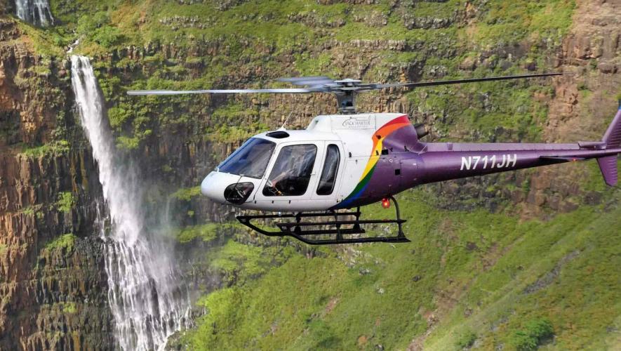 Jack Harter Helicopters Eurocopter AS 350 B2 in flight off Hawaiian coast with waterfall in background
