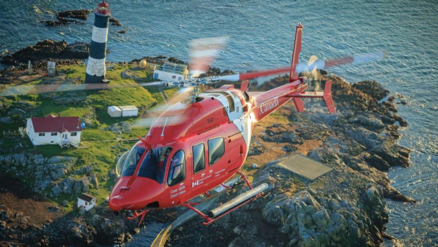 Canadian Coast Guard Bell 429 helicopter in flight over coast with lighthouse