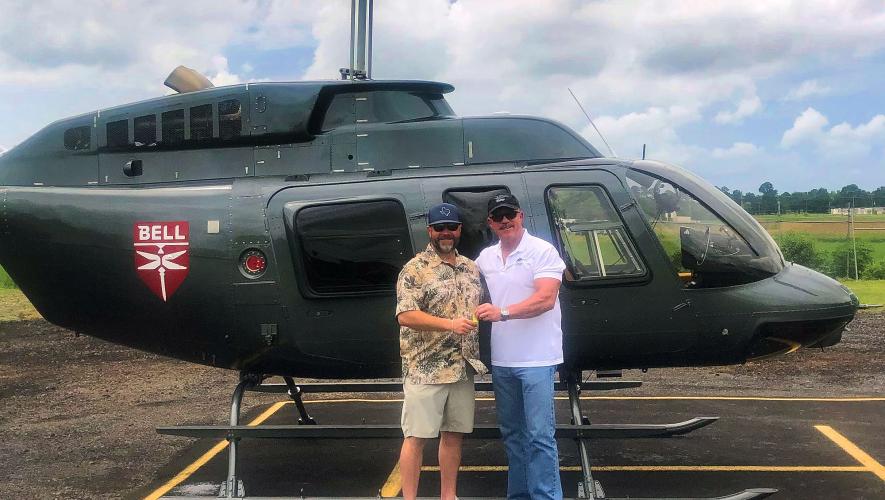 Michael Bashlor, the Managing Partner at Meridian Helicopters (right) handing keys of refurbished Bell 206L4 to Kevin Reed with helicopter in background. 