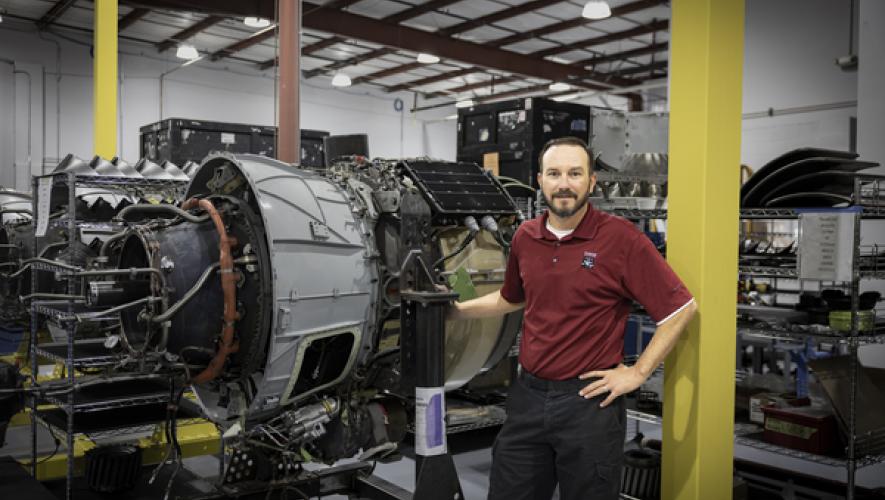 Shawn Schmitz, Duncan Aviation HTF7000 program manager poses by Honeywell HTF7000 engine in new shop