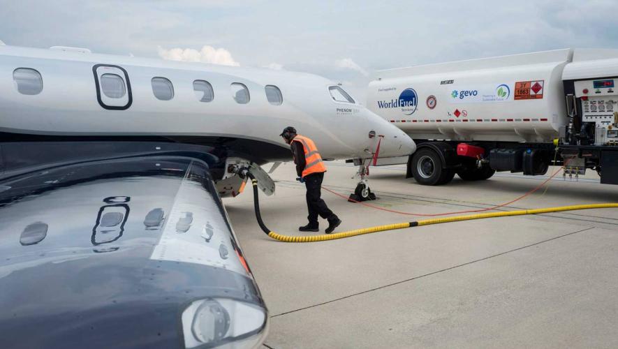 Line worker refueling business jet with sustainable aviation fuel from tanker truck