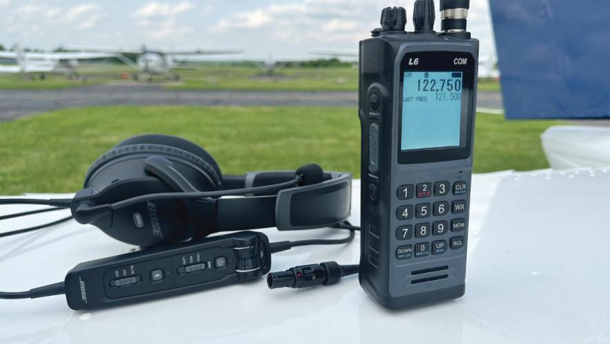 L6 COM Radio with headset displayed on aircraft wing with other aircraft in background