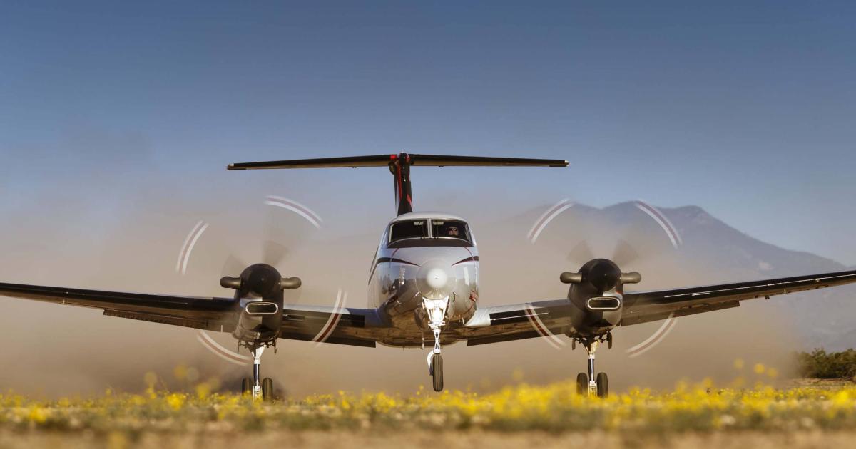 Front view of Beechcraft King Air 360 on takeoff from grass strip backdropped with mountains