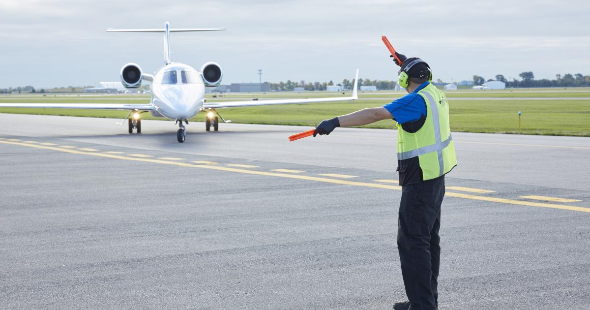 FBO line service technician marshalling an airplane