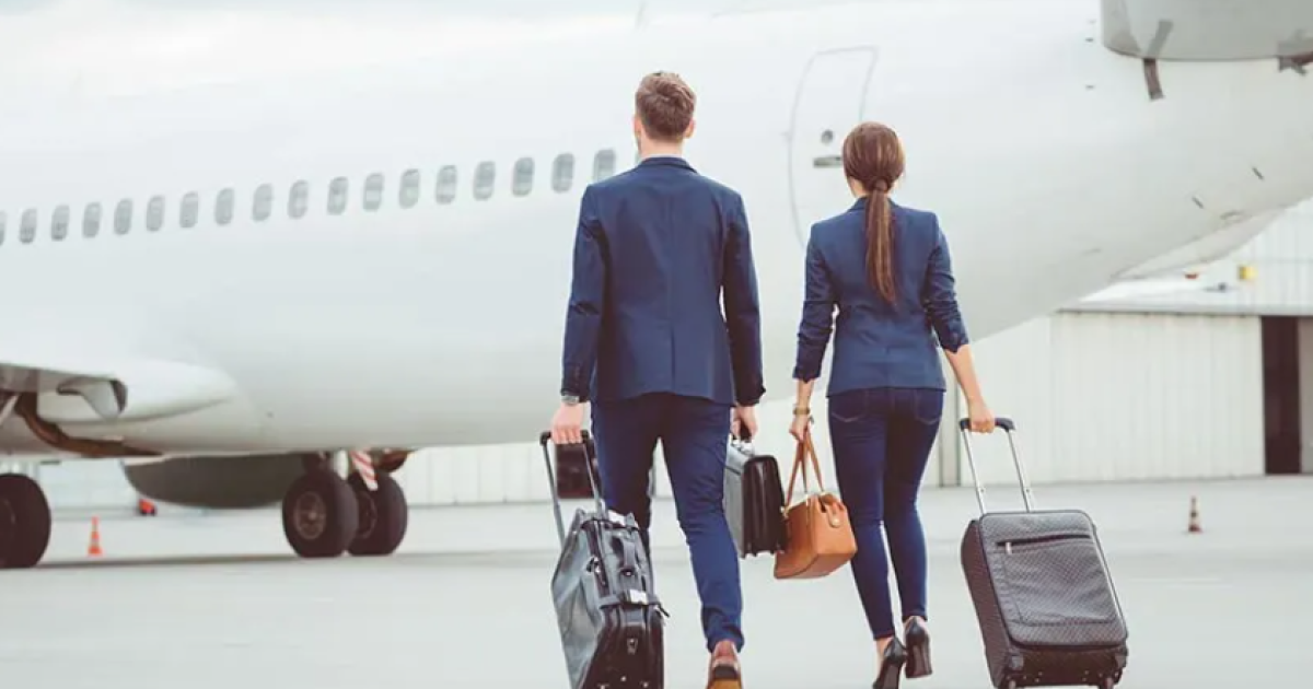 Two people with suitcases walking towards white aeroplane 