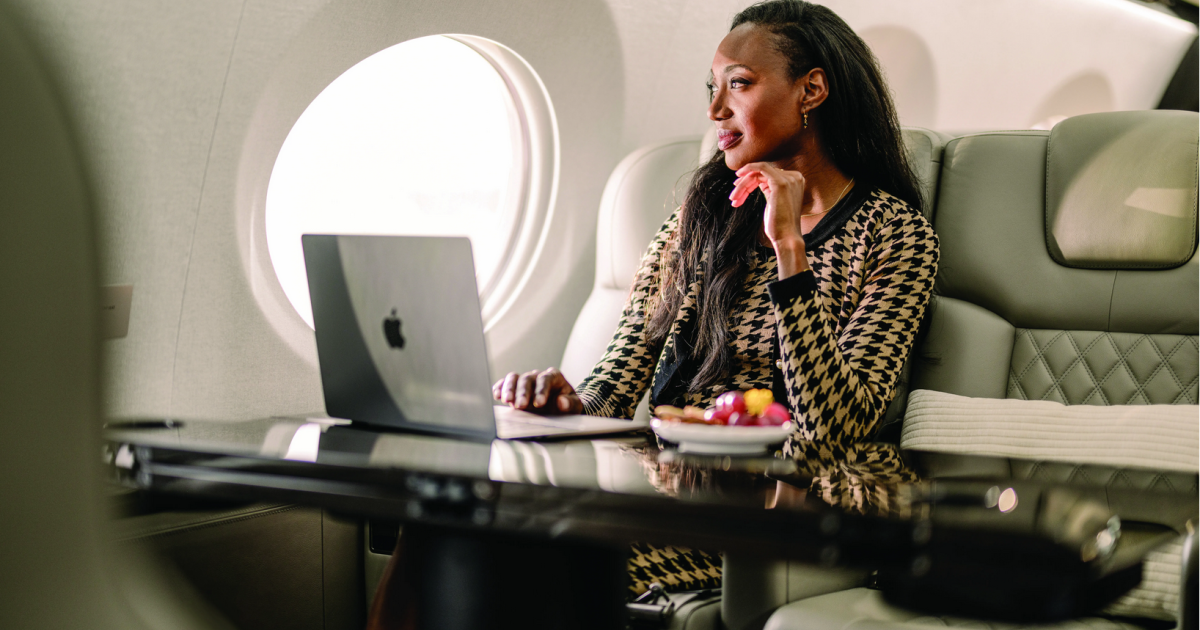 A woman sits in an aircraft cabin with her laptop