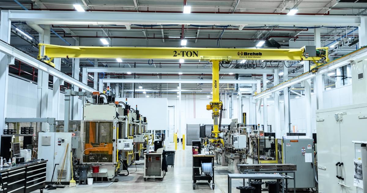 An interior shot of a brightly-lit advanced composite manufacturing production facility with clean concrete floors, moveable fixtures, overhead lift, and advanced tooling.