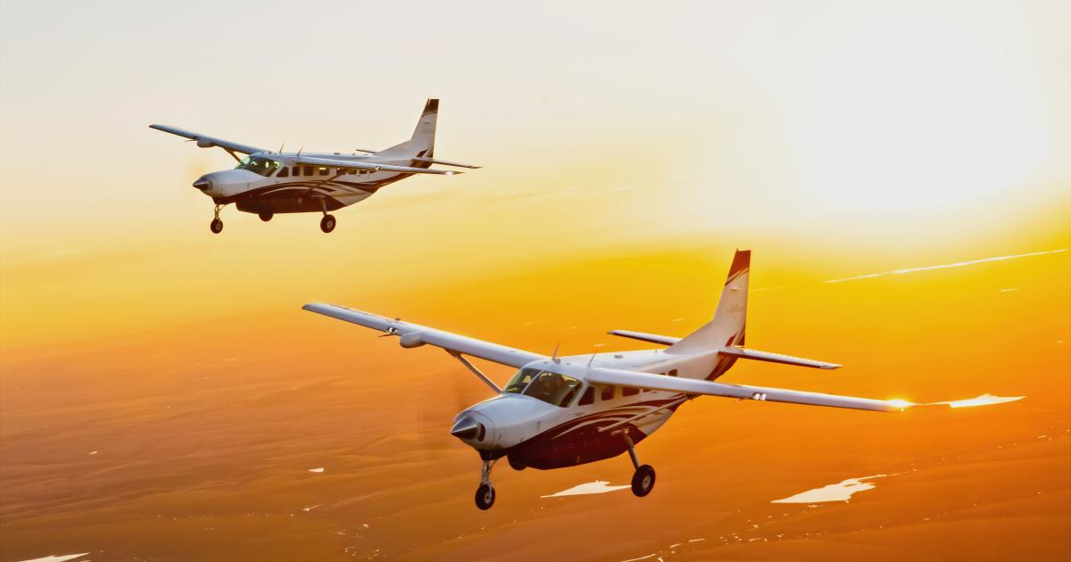 Two Cessna Caravans in flight against sunset 