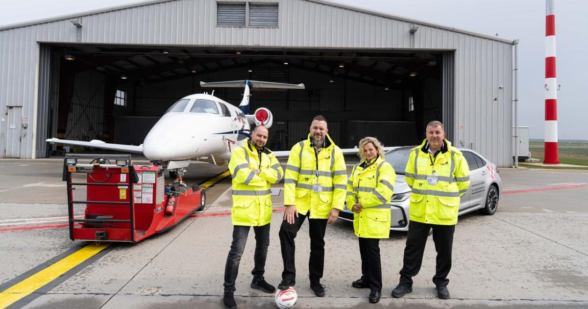four people standing outside hangar 