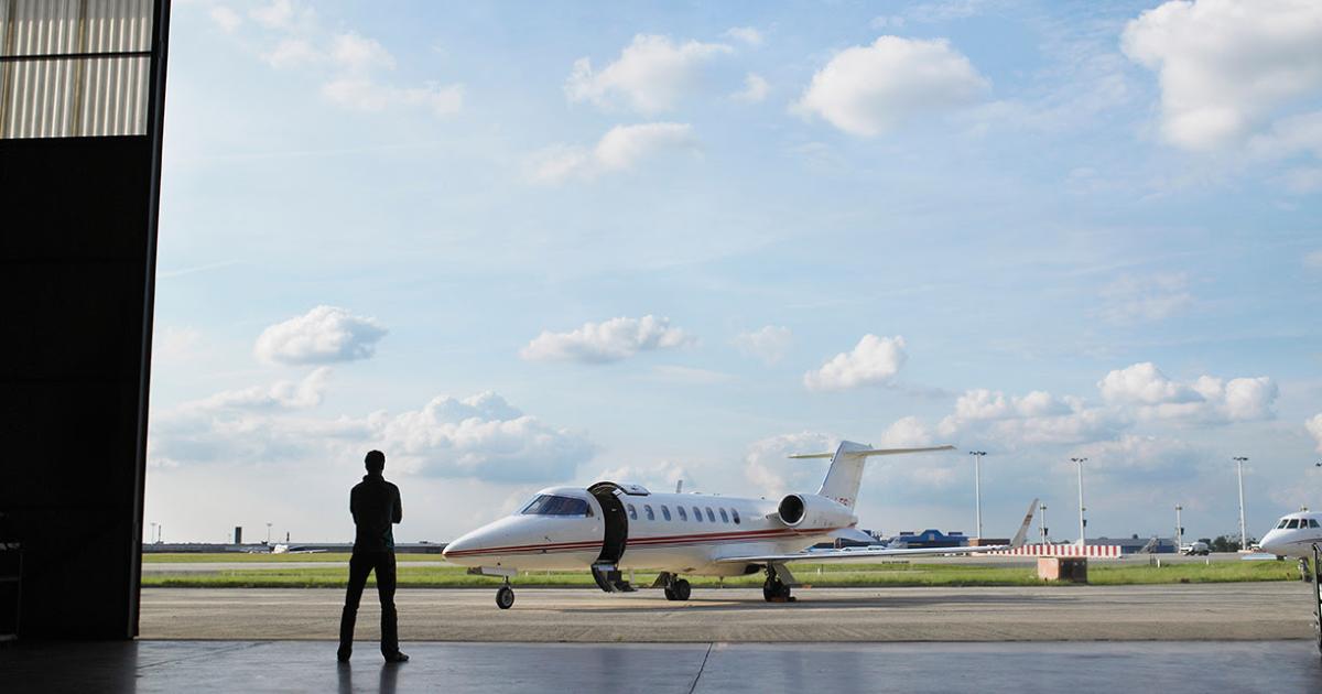 Nimbl image silhouette of a person standing in a hangar door looking at an aircraft on the ramp